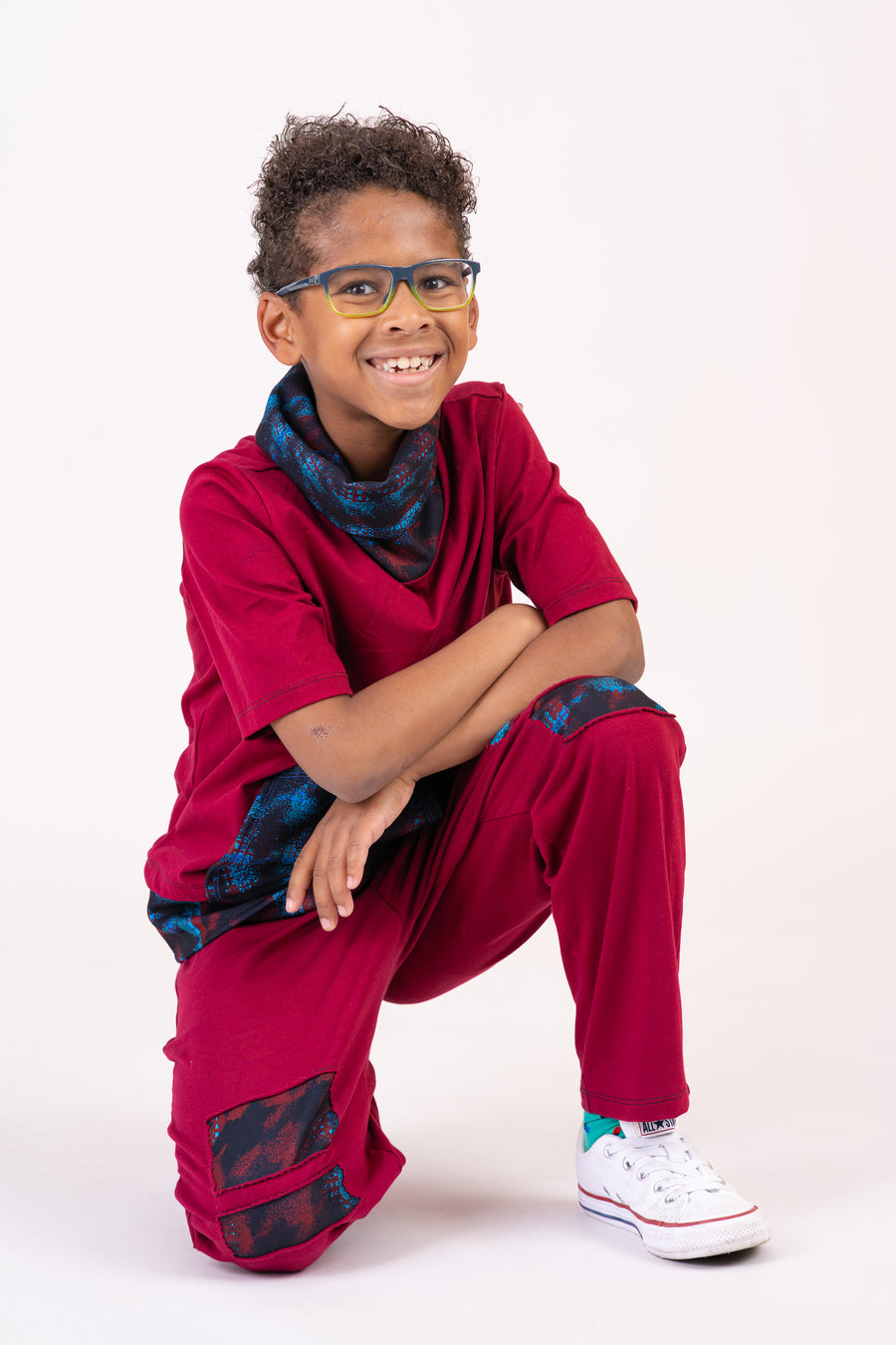 Boy smiling in a burgundy outfit with colorful patterned accents
