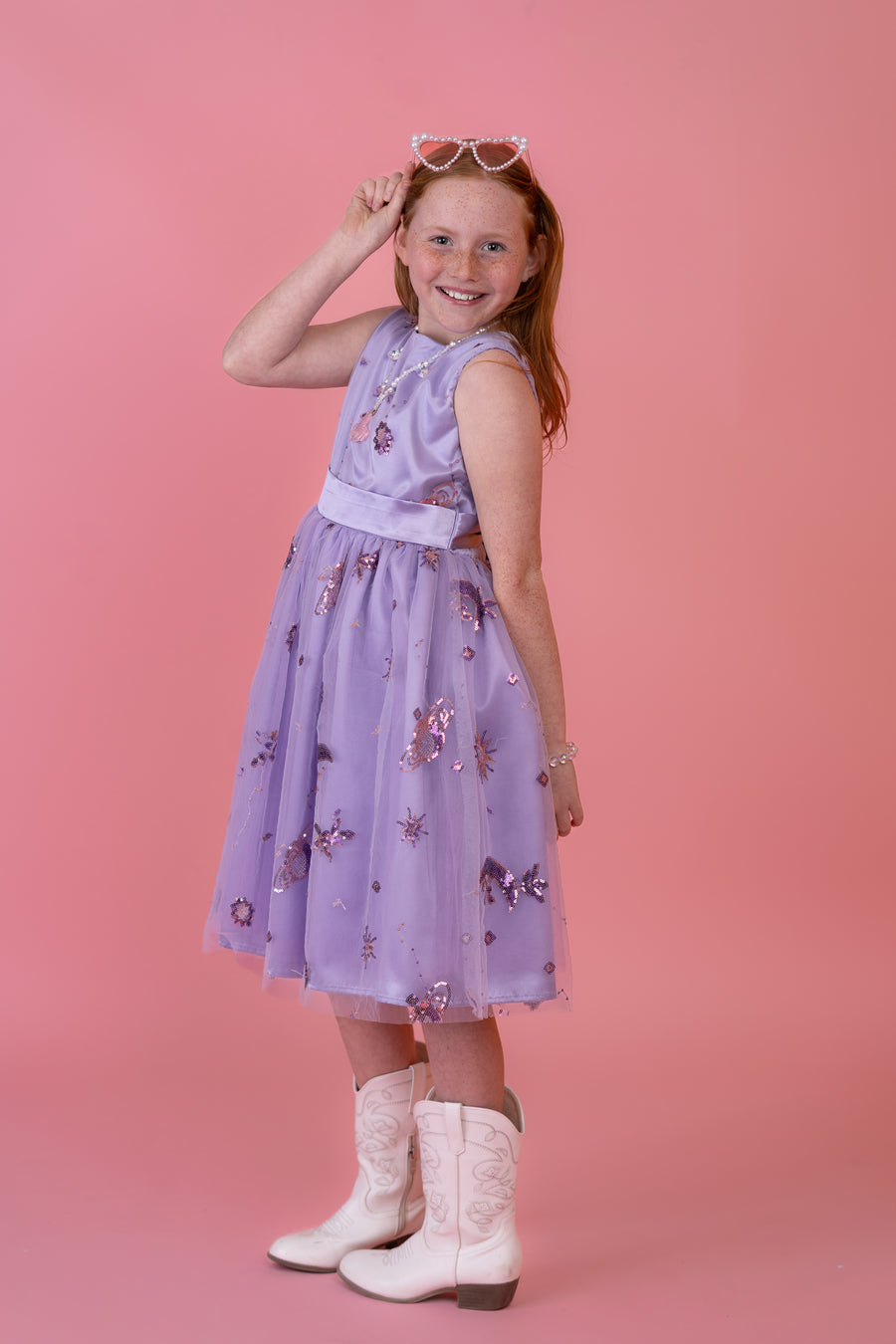 Girl wearing a lavender butterfly dress against a pink backdrop